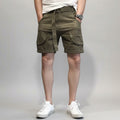Person wearing olive green cargo shorts on a gray background, Obroi