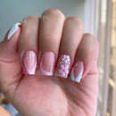 Hand with pink and white floral nail art on a blurred background, Obroi