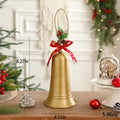 A gold Christmas bell decoration with a hanging loop, decorated with a red ribbon bow, pinecones, and greenery. The image includes dimension lines showing 21cm height, 11cm bell diameter, and a weight of 169g, set on a wooden table with holiday decorations in a festive room background, Obroi
