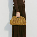 Person holding a mustard yellow woven handbag against a plain background, Obroi