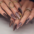 Close-up of hands with dark nail polish and gold rings on a neutral background, Obroi