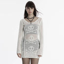 Woman wearing a white crochet dress with skull designs on a plain background