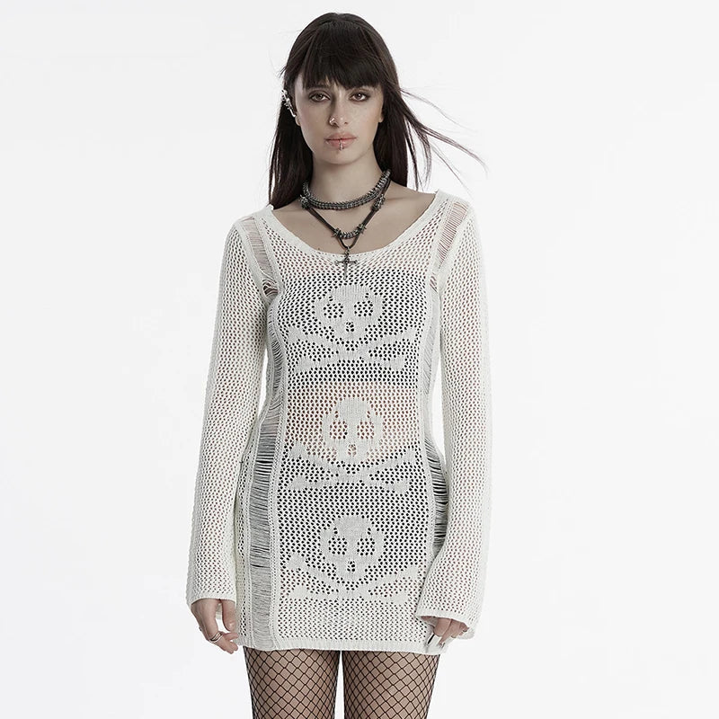 Woman wearing a white crochet dress with skull designs on a plain background