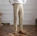 Person wearing beige pants and a white shirt in a room with wooden flooring and white walls, Obroi