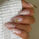 Close-up of a hand with pink nails featuring gold designs on a textured white background, Obroi