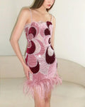 Woman wearing a pink and maroon dress with feather details on a white background, Obroi