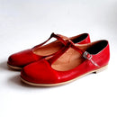 Pair of red leather shoes with a strap and buckle on a white background, Obroi