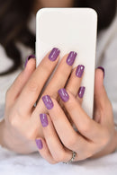 Close-up of hands with purple nail polish holding a white phone, Obroi