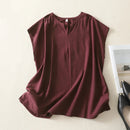 Maroon sleeveless top on a light beige surface with black high-heeled shoes and a white card in the background, Obroi