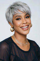 Woman with short gray hair smiling against a light background, Obroi