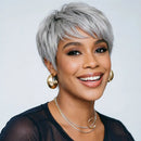 Woman with short gray hair wearing gold earrings and a necklace against a white background, Obroi
