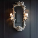 Decorative mirror with floral frame and wall sconces on a dark paneled wall, Obroi