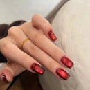 Hand with red nail polish and a gold ring on a neutral background, Obroi