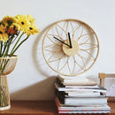 Decorative clock on a stack of books with yellow flowers in the background, Obroi