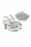 Silver high-heeled shoes with embellishments and a matching clutch on a white background, Obroi