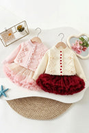 Two toddler girls' cardigan and tutu dress sets displayed on wooden hangers. The set on the left is light pink, featuring a pink knit cardigan with scalloped edges and pom-pom details, paired with a layered tulle tutu skirt, Obroi