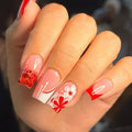 Close-up of a hand with red and white floral nail art on a blurred background, Obroi