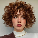 Woman with curly brown hair wearing a white top and brown jacket against a neutral background, Obroi