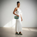 Woman in a white dress holding a green handbag against a plain background, Obroi