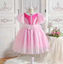 Pink princess dress on a mannequin against a decorative white wall, Obroi