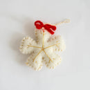 White felt snowflake ornament with a red bow on a light gray background, Obroi