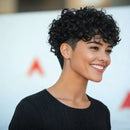 Woman with short, curly black hair smiling against a blurred background, Obroi