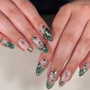 Close-up of hands with decorative nail art featuring flowers and stars on a neutral background, Obroi