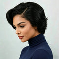 Woman with styled black hair wearing a blue turtleneck against a light gray background, Obroi