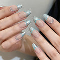 Nails with decorative silver and blue designs on a neutral background, Obroi