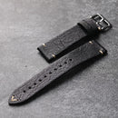 Black leather watch strap on a gray surface, Obroi