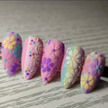 Colorful flower-patterned rocks on a wooden surface, Obroi