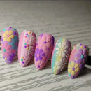 Colorful flower-patterned rocks on a wooden surface, Obroi