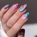 Hand with marbled nail art featuring pink, blue, and green colors.