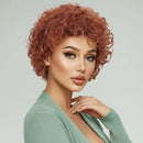 Woman with styled red hair wearing a green cardigan against a light gray background, Obroi