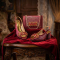 Pair of red high-heeled shoes with embellishments and a matching handbag on a red cloth, Obroi