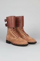 Pair of brown suede boots with leather straps on a light gray background, Obroi