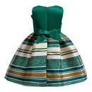 A strapless children's dress shown from the back, featuring a solid emerald green satin back panel and bow, with a pleated skirt in horizontal stripes of green, white, gold, and brown on a white background, Obroi