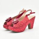 A pair of red platform slingback heels with gold floral embroidery, rhinestone embellishments, and flower appliqués with pearl centers, shown on a white background, Obroi