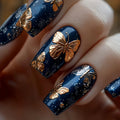 Nails with blue and gold butterfly design on a blurred background, Obroi