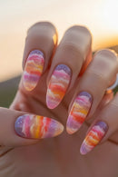 Nails with colorful watercolor design held against a blurred natural background, Obroi