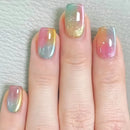 Nails with a gradient design in pink, yellow, and blue on a light gray background, Obroi