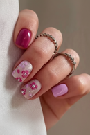 Hand with pink floral nail design on a neutral background, Obroi