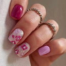 Hand with pink and white floral nail design on a neutral background, Obroi