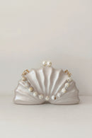 Shell-shaped handbag with pearl detailing on a light background, Obroi