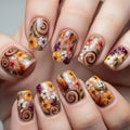 Nails with autumn-themed floral and swirl designs, Obroi