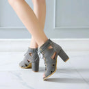 Gray high-heeled shoes with cut-out design worn by a person on a light wooden floor, Obroi