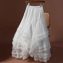 White ruffled skirt on a hanger against a brown background, Obroi