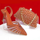 Orange high-heeled shoe with clear sole and matching clutch on a red background, Obroi