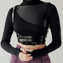 Person wearing a black leather harness over a black turtleneck and purple pants on a gray background, Obroi