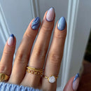 Hand with blue and pink nail polish wearing gold rings against a neutral background by obroi